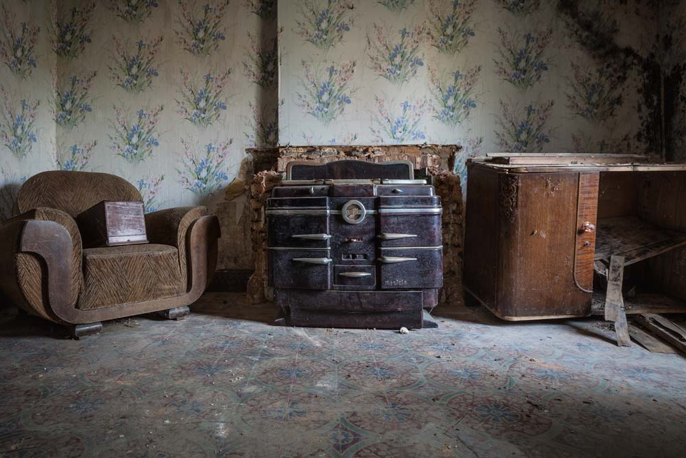 Ferme Fritel urbexlocatie in België. De huiskamer met een prachtige oude kachel en wat meubeltjes.