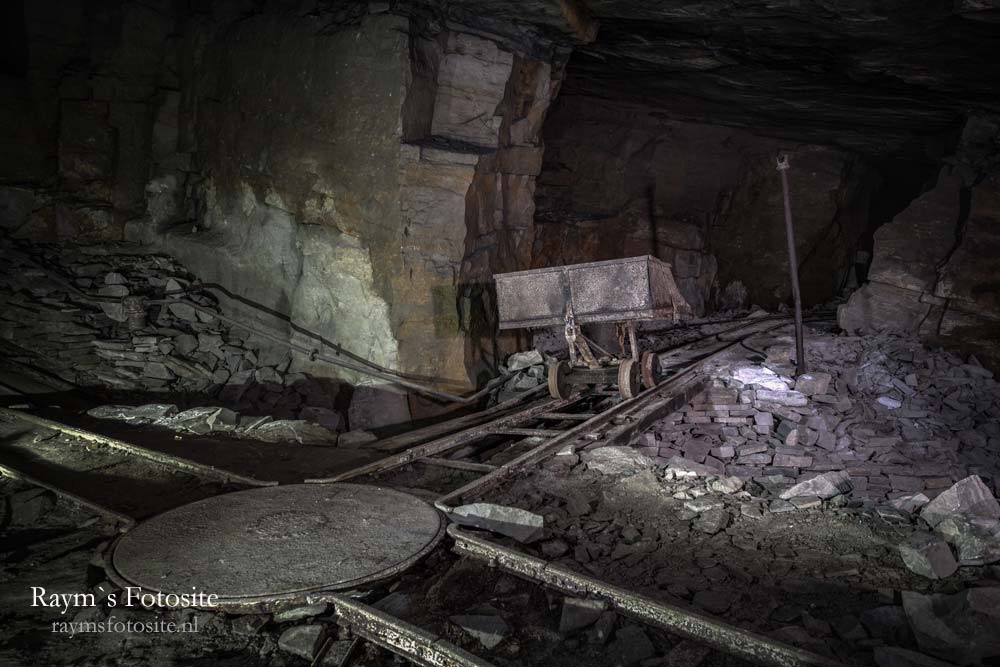 Een verlaten steengroeve met rails en mijnwerkers karretjes.