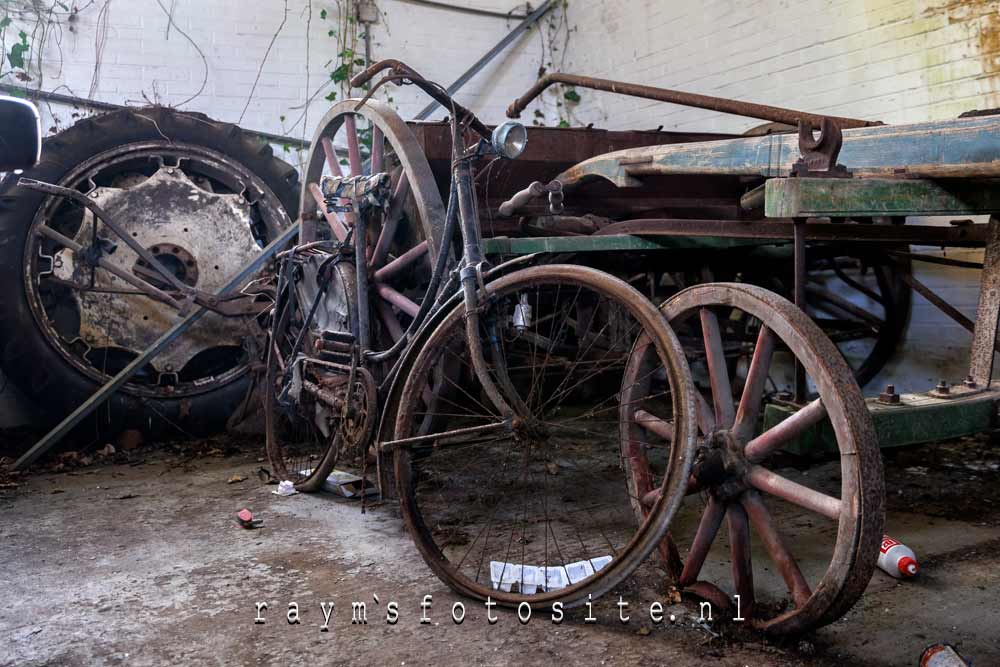 Urbex in Nederland. Een loods met verlaten auto`s, oude fietsen en een motor.