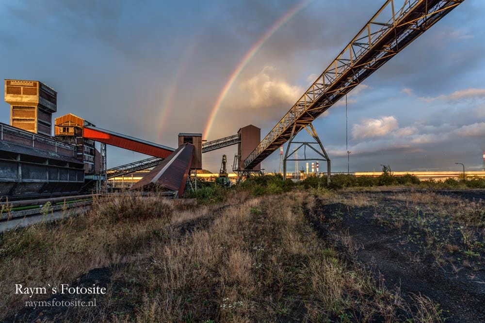 Verlaten staalfabriek in België met een mooie regenboog erboven.